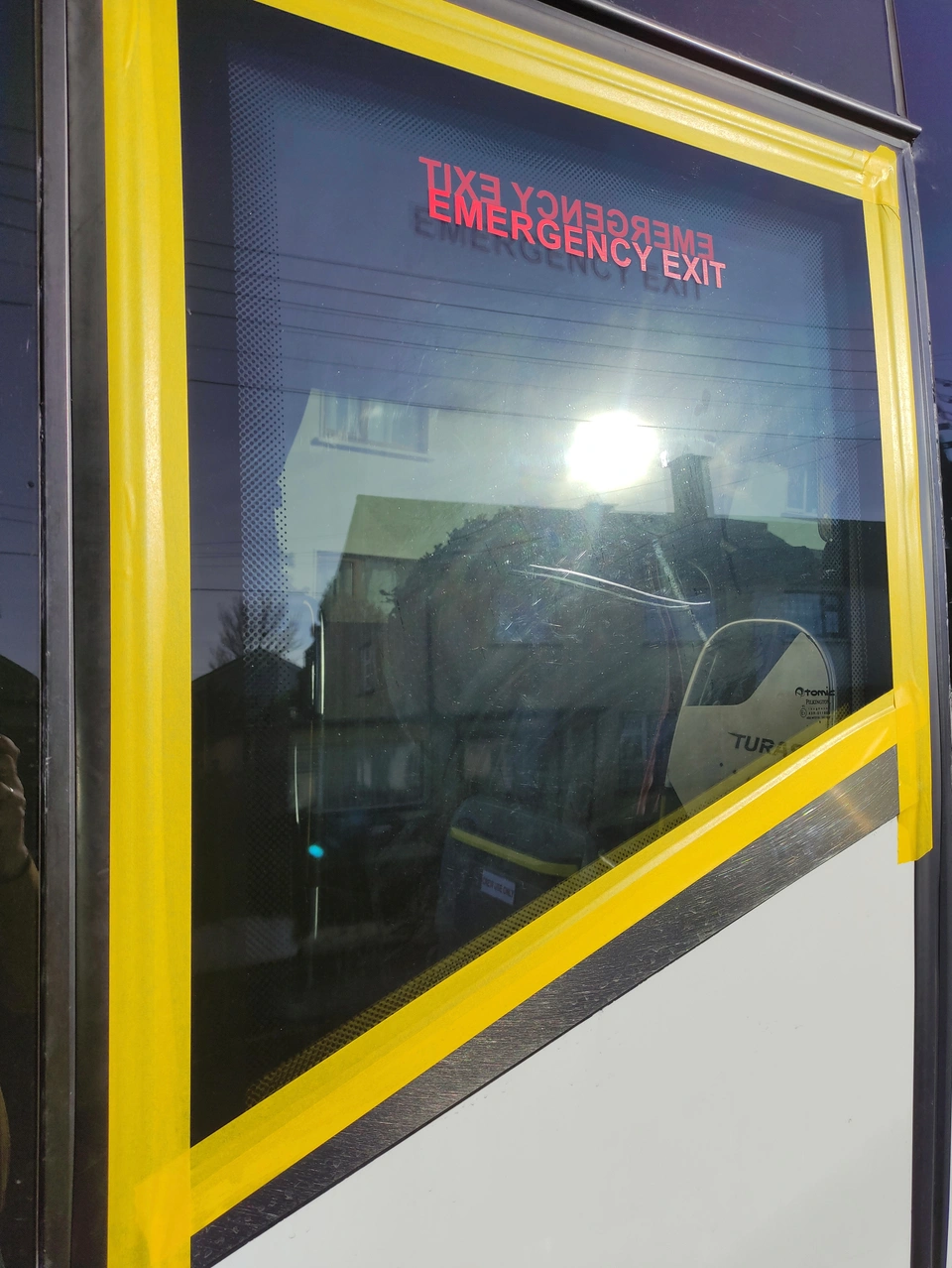 Coach side window before restoration, with visible scratches and yellow tape around the glass.