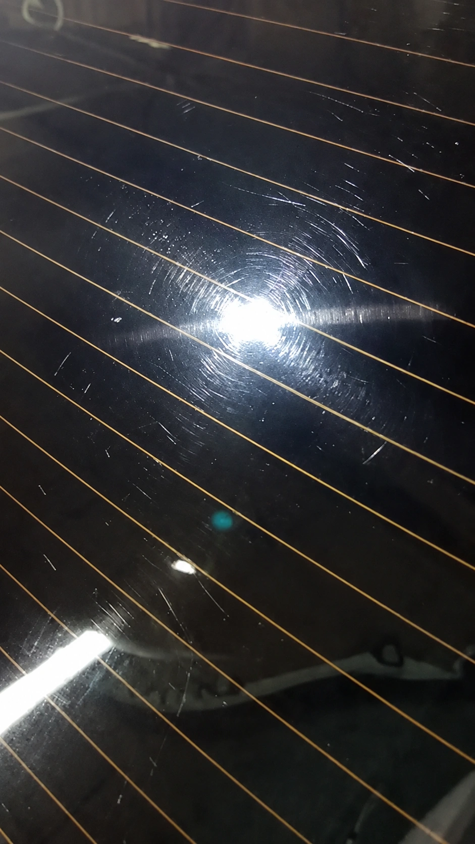 Rear window before restoration, with scratches visible around a light reflection and heating lines.